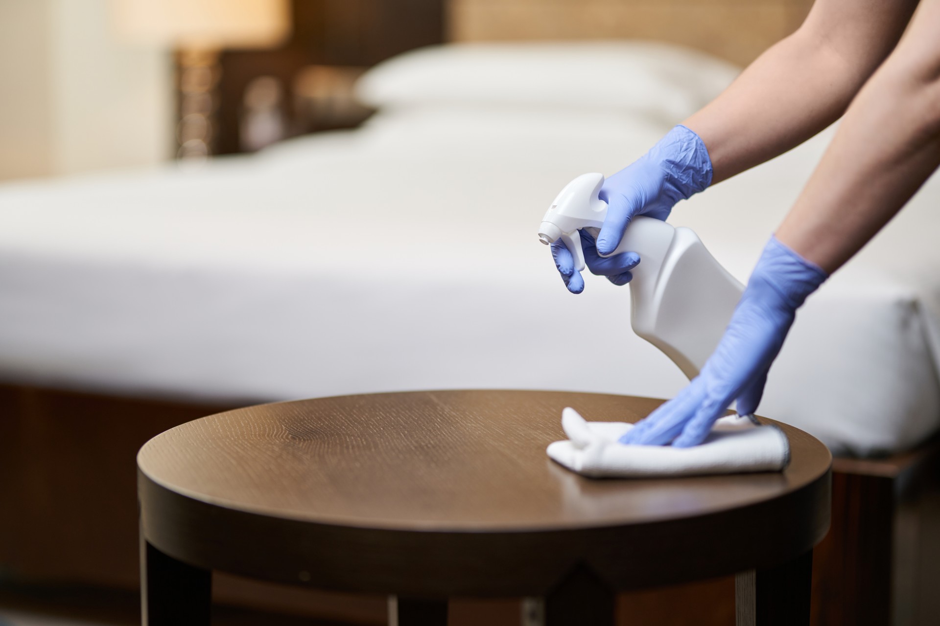 Housemaid wiping bedside table in the bedroom